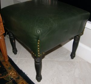3166:: Footstool, ca.1785, square, reupholstered in green leather employing brass tacks at the folds, supported on four turned legs painted black, original dry patina